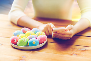 Image showing close up of hands with easter eggs and smartphone