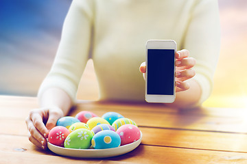 Image showing close up of hands with easter eggs and smartphone