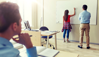 Image showing teacher and student writing on board at school