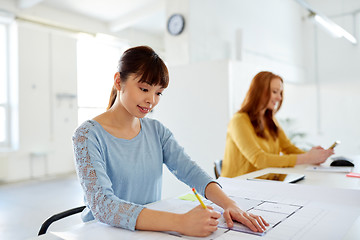 Image showing female architect with blueprint working at office