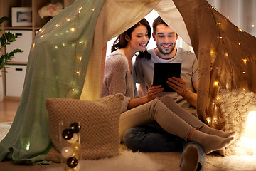 Image showing happy couple with tablet pc in kids tent at home
