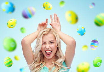 Image showing happy woman making bunny ears over easter eggs