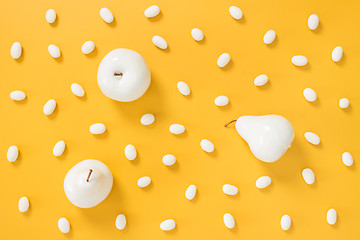 Image showing White chocolate candies and painted fruits on yellow background