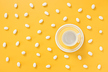 Image showing White chocolate candies and teacup on yellow background