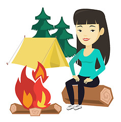 Image showing Woman sitting on log near campfire in the camping.