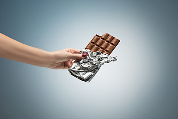 Image showing Hands of a woman holding a tile of chocolate