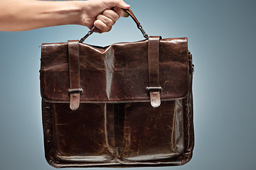 Image showing A man holding a brown leather travel bag