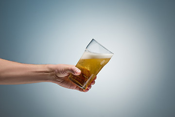 Image showing Closeup of a male hand holding up a glass of beer