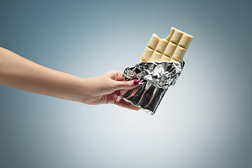 Image showing Hands of a woman holding a tile of chocolate