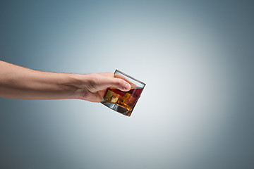 Image showing Hand holding a glass of whiskey