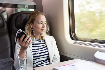 Image showing Businesswoman communicating on mobile phone while traveling by train.