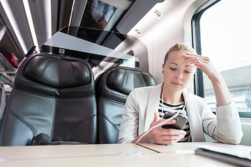 Image showing Businesswoman communicating on mobile phone while traveling by train.