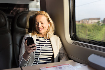 Image showing Businesswoman communicating on mobile phone while traveling by train.