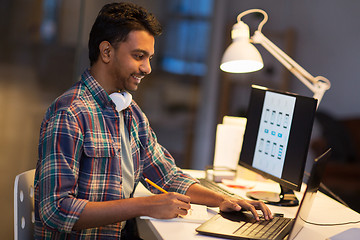 Image showing creative man with laptop working at night office