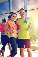 Image showing smiling couple with water bottles in gym