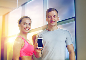 Image showing smiling young woman with personal trainer in gym