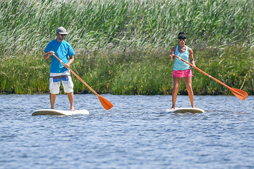 Image showing Man and woman stand up paddleboarding