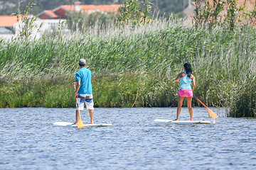 Image showing Man and woman stand up paddleboarding