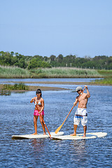 Image showing Man and woman stand up paddleboarding