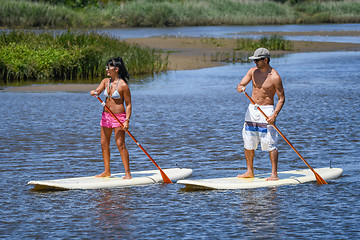 Image showing Man and woman stand up paddleboarding
