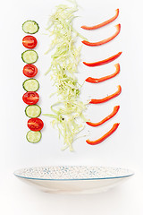 Image showing The salad bowl in flight with vegetables: tomato, cucumber, cabbage on white background