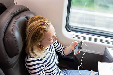 Image showing Woman communicating on mobile phone while traveling by train.