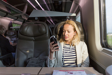 Image showing Businesswoman communicating on mobile phone while traveling by train.