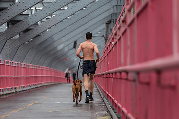 Image showing Unrecognizable topless recreational runner and a dog at Williamsburg bridgein New York CIty, USA.