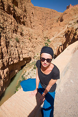 Image showing Image of female tourist relaxing on winding road bank in Dades Valley, Atlas mountains, Morocco.