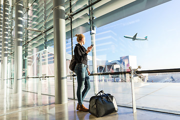 Image showing Young woman waiting at airport, looking through the gate window.