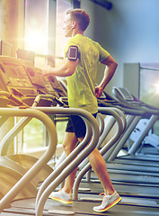 Image showing man with smartphone exercising on treadmill in gym