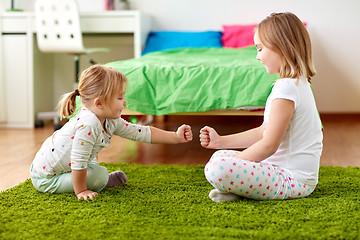 Image showing girls playing rock-paper-scissors game at home