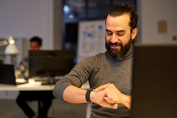 Image showing creative man with smartwatch at night office