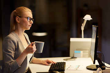 Image showing businesswoman at night office drinking coffee