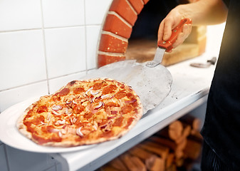 Image showing chef placing pizza from peel to plate at pizzeria