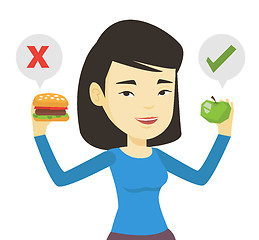 Image showing Woman choosing between hamburger and cupcake.