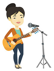 Image showing Woman singing in microphone and playing guitar.