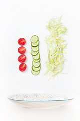 Image showing The salad bowl in flight with vegetables: tomato, cucumber, cabbage on white background