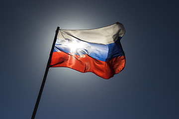 Image showing russian flag flying in slow motion and back lit by the sun.