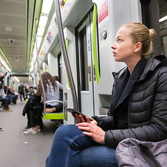 Image showing Young girl with mobile phone traveling on metro.