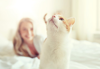 Image showing happy young woman with cat in bed at home