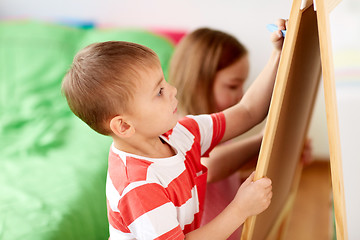 Image showing happy kids drawing on chalk board at home