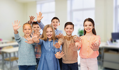 Image showing happy students waving hands at school