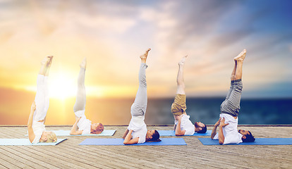 Image showing people doing yoga shoulderstand on mat outdoors