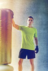 Image showing man with boxing gloves and punching bag in gym