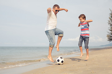 Image showing Father and son playing football on the beach at the day time.