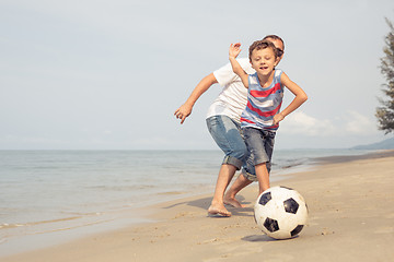 Image showing Father and son playing football on the beach at the day time.