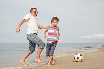 Image showing Father and son playing football on the beach at the day time.