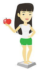 Image showing Woman standing on scale and holding apple in hand.