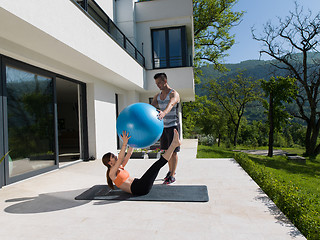 Image showing woman and personal trainer doing exercise with pilates ball